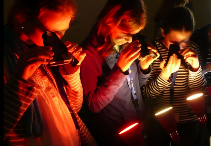 Die Mädchen untersuchen mit ihren selbst gebastelten Handspektroskopen verschiedene Lichtquellen.